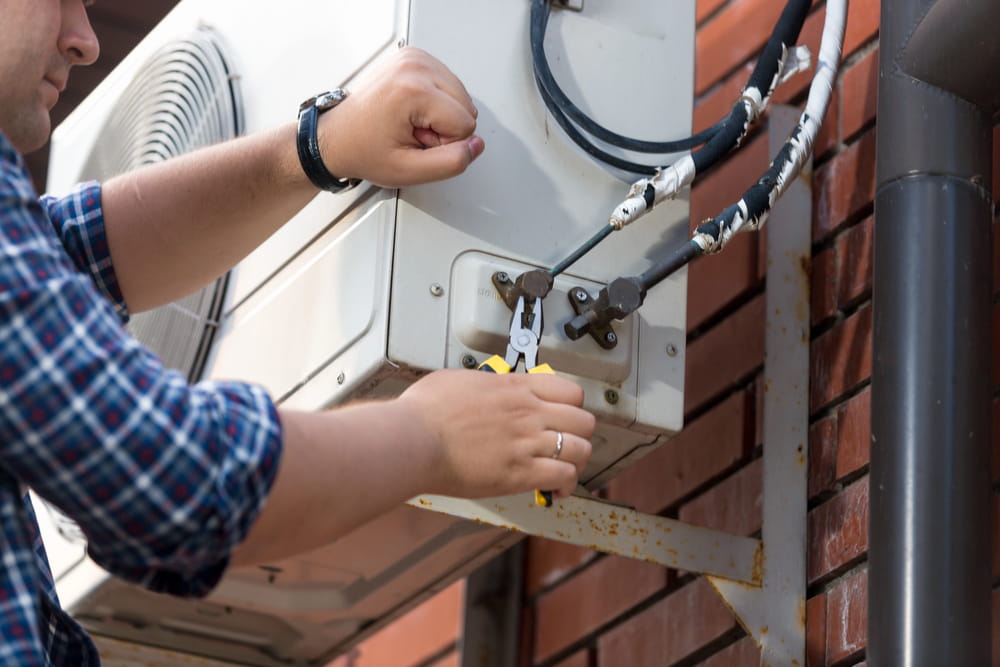 Closeup of male technician repairing outdoor ac uni