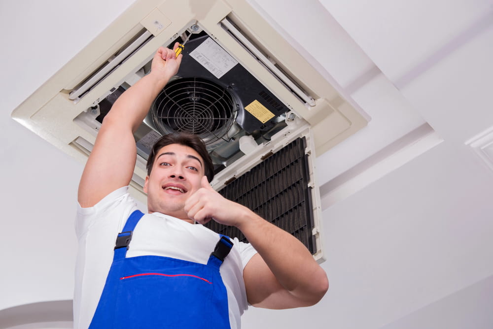 Worker repairing ceiling air conditioning unit